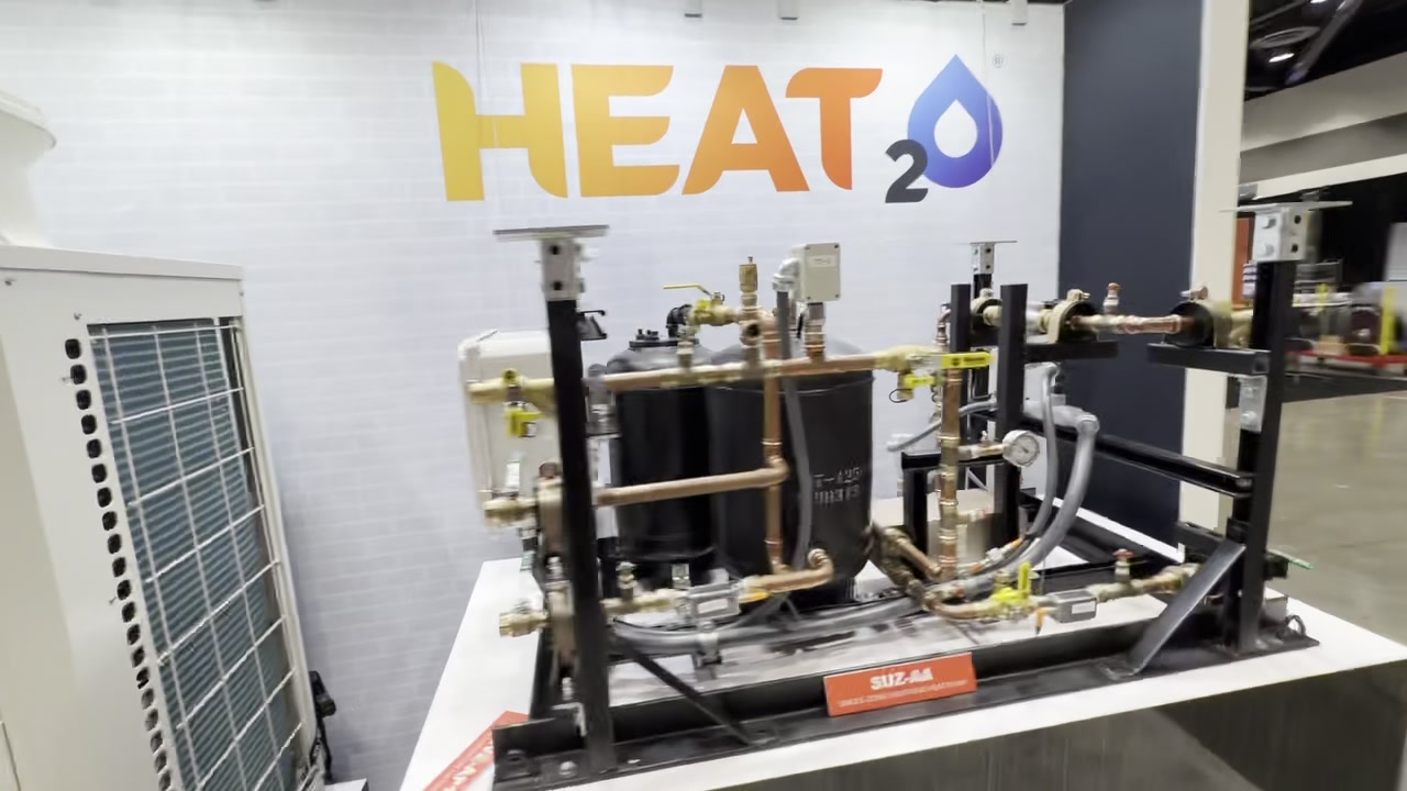 Exposed Mitsubishi Electric HVAC mechanical equipment with copper piping, gauges, and HEAT2O display graphic.
